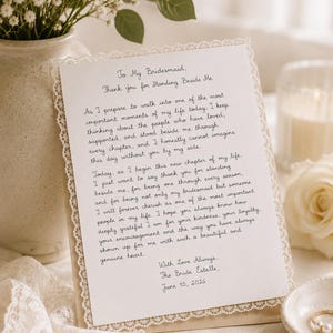 Puede incluir: Una carta manuscrita crema con borde de encaje, dirigida a "To My Bridesmaid". El texto expresa gratitud y amor, firmado "The Bride Estelle, June 10, 2026". Un jarrón con flores blancas y una vela están en el fondo.