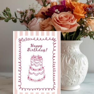 Puede incluir: Una tarjeta de cumplea&ntilde;os con un fondo a rayas rosas y blancas y un borde decorativo. La tarjeta presenta un dibujo de una tarta de varios pisos con cerezas y las palabras "Happy Birthday!". Un ramo de flores coloridas est&aacute; en un jarr&oacute;n blanco.