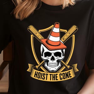 May include: Black t-shirt featuring a graphic of a skull wearing an orange and white traffic cone, with crossed baseball bats behind it. The text "HOIST THE CONE" is displayed on a banner below the skull.