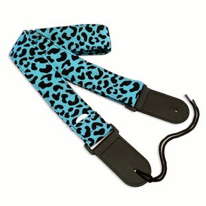 Puede incluir: Una correa de guitarra de estampado de leopardo azul y negro con longitud ajustable y extremos de cuero negro.
