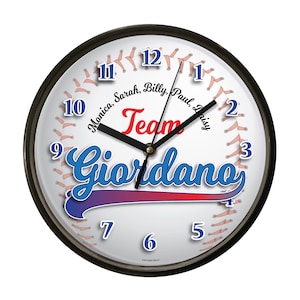 May include: A round wall clock with a black frame. The clock face resembles a baseball, with red stitching and the word "Team" in red. The name "Giordano" is in blue and purple, with the numbers 1-12 around the edge.