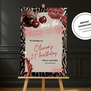 Op de afbeelding: Een feestbord op een ezel met een luipaardprint rand. Het bord luidt "she's the Cherry on top" en verwelkomt gasten op Olivia's 21e verjaardag op 16 april 2025. Bevat een discobal, kersen en rode lippen.
