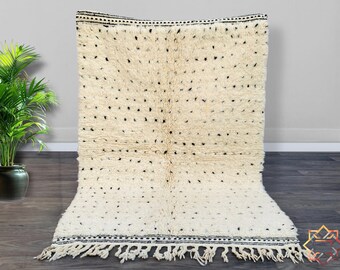 May include: A white and black Moroccan rug with a geometric pattern. The rug has a fringe border and is made of wool.