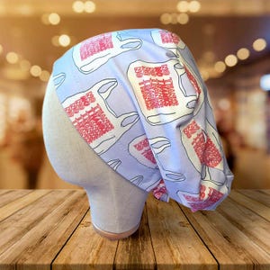May include: A light blue surgical scrub cap with a repeating pattern of white takeout containers and the text "NO THANKS" in red. The cap is displayed on a mannequin head.