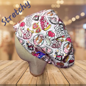 May include: A white and pink patterned scrub cap with an Alice in Wonderland theme. The cap features illustrations of hearts, playing cards, a rabbit in a hat, and the text "Pink Pony Club". The word "Stretchy" is written in blue.