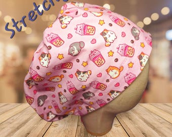 May include: Pink surgical scrub cap with a repeating pattern of cartoon cats, boba tea, and stars. The word "Stretchy" is written in blue script across the top. The cap is displayed on a mannequin head.