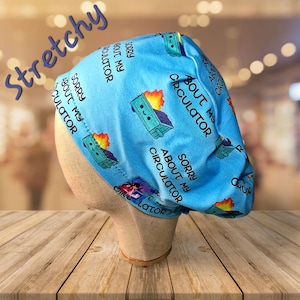 May include: A blue scrub hat with a repeating pattern of a cartoon dumpster on fire and the text "Sorry about my circulator".