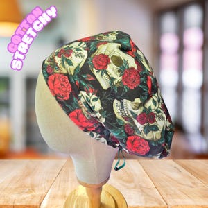 May include: A cotton stretchy skull cap with a black background, featuring a pattern of white skulls and red roses. The cap is displayed on a mannequin head. The words "COTTON STRETCHY" are printed on the upper left side.