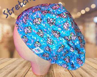May include: A blue and pink stretchy surgical scrub hat with a unicorn print. The hat has a white label with the word "Stretchy" on it.