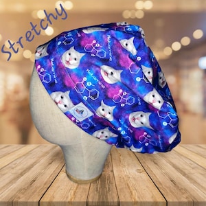 May include: A blue and purple stretchy scrub hat with a white cat face and the text "Ketamine" repeated on the fabric.
