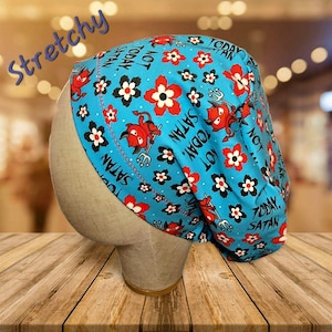 May include: A blue surgical scrub cap with a repeating pattern of red devil figures, red and white flowers, and the text "NOT TODAY, SATAN." The word "Stretchy" is written in blue script across the top.