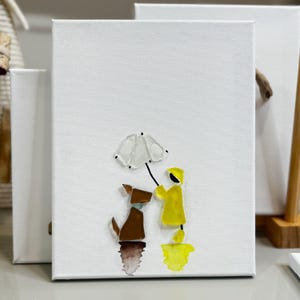May include: A white canvas art piece features a dog and a person in a yellow raincoat under a white umbrella. The dog is brown and the person is yellow. The artwork is on a white background.
