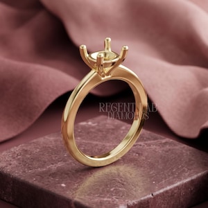 May include: A polished yellow gold ring setting featuring a four-prong head designed to hold a single gemstone. The band is smooth and rounded. The text REGENT LAB DIAMONDS is visible on the side of the ring shank in a clean, sans-serif font.