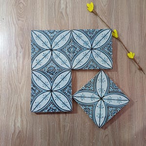 Op de afbeelding: Een set van drie keramische nestkommen in blauwe, groene en witte tinten. De kommen hebben een gespikkelde glazuur en een eenvoudig, modern ontwerp. De grootste kom heeft een diameter van ongeveer 15 cm.