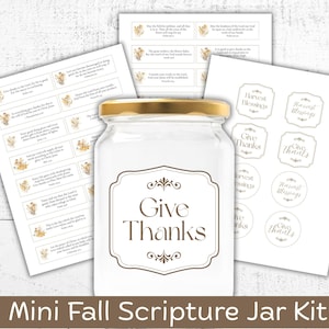 May include: A clear glass jar with a gold lid and a label that reads "Give Thanks" in brown script. The jar is part of a "Mini Fall Scripture Jar Kit" with coordinating labels and stickers featuring fall-themed graphics and Bible verses.