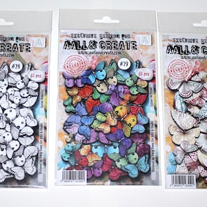 Op de afbeelding: Drie pakketten vlinderversieringen. Het eerste pakket bevat zwart-witte vlinders, het tweede kleurrijke vlinders en het derde vlinders in beige en roze tinten. Elk pakket is voorzien van de merknaam en het aantal stuks.