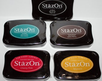 May include: Five black ink pads with the brand name "StazOn" printed on each. The ink pad colors are jet black, teal blue, timber brown, cherry pink, and mustard.