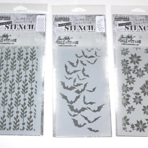 May include: Three stencils in clear plastic packaging. Designs include a leafy pattern, a flock of bats, and a floral arrangement. The stencils are labeled "Layering Stencil" and are from the "Tim Holtz Collection."
