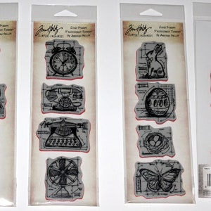 May include: Four clear plastic packages containing sets of rubber stamps. Each set features a different theme: sewing, home, bunny, and baby. The stamps are black and white and have a vintage style.