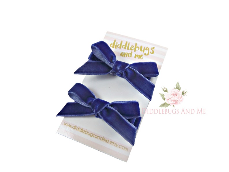 May include: Two navy blue velvet hair bows on a white card with the text "diddlebugs and me" and the website address "www.diddlebugsandme.etsy.com".
