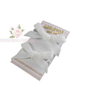 May include: Three white satin ribbon bows with a small card that says "Diddlebugs and Me" and a website address.