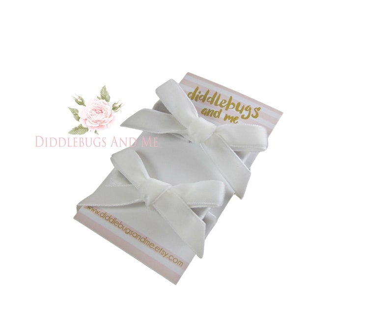 May include: Three white satin ribbon bows with a small card that says "Diddlebugs and Me" and a website address.