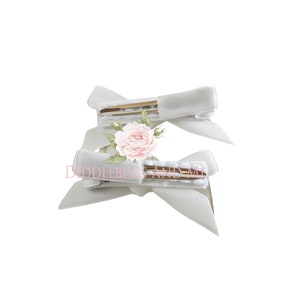May include: Two white satin hair clips with gold clips. The clips are tied into bows.