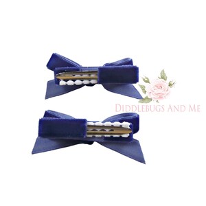 May include: Two navy blue velvet hair bows with white polka dot clips.