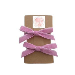 May include: Two pink velvet hair bows on a brown card with a logo that says "D&M Hair Jewelry".