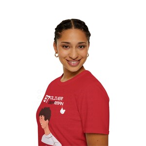 May include: A red t-shirt with a white graphic of a cartoon person with the text "87 Oliver Berriman".