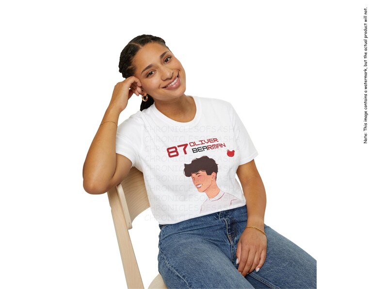 May include: A white t-shirt featuring a red and black graphic of a person with the text "87 Oliver Bearman" on it.