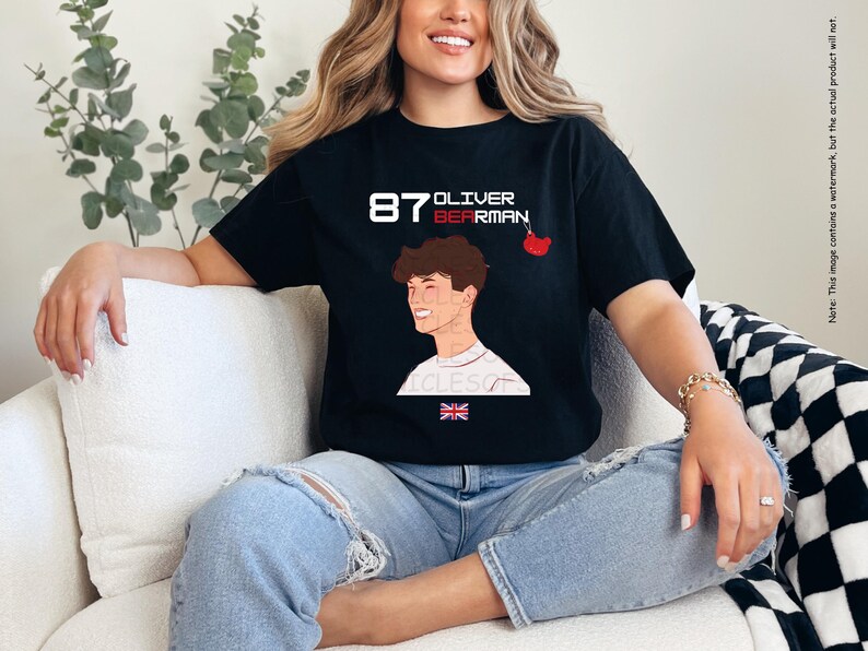 May include: Black t-shirt featuring a white graphic of a racing driver with the text "87 Oliver Bearman" and a small red cherry design.