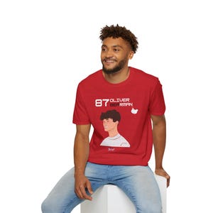 May include: A red t-shirt with a white graphic of a person's face and the text "87 Oliver Bierman".