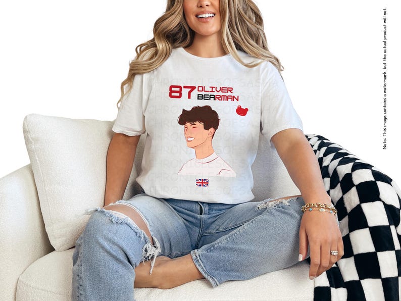 May include: White t-shirt featuring a graphic of a young man with the text "87 Oliver Bearman" printed on it. The graphic also includes a small red bear icon.