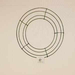 May include: A green metal wreath frame with a circular shape and multiple rings. The frame is designed for crafting and decorating.