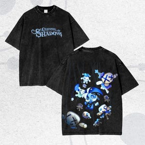 May include: Black t-shirt with the text "Carnival of Shadows" in light blue on the front. The back of the shirt features a graphic of blue and white puppet-like characters. The shirt has a vintage, washed-out look.