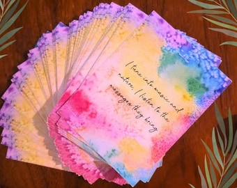 May include: A deck of colorful cards with watercolor designs in shades of pink, blue, yellow, and purple. Each card has the text "I tune into music and nature. I listen to the messages they bring."