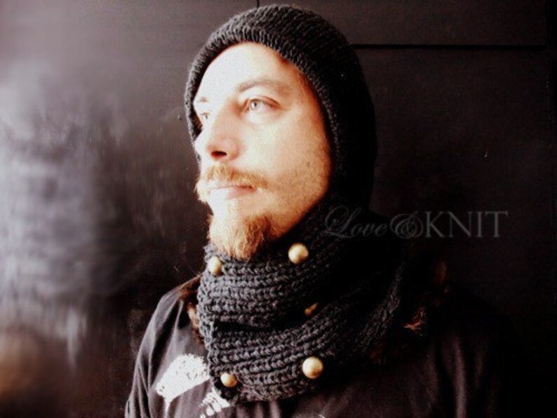 May include: A black knit hat and matching scarf with gold buttons. The hat is pulled down over the person's forehead.