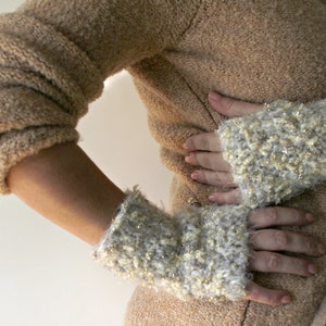 May include: A pair of white and gold fingerless gloves with a fuzzy texture.