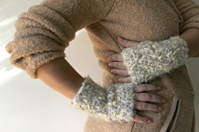 May include: A pair of white and gold fingerless gloves with a fuzzy texture.