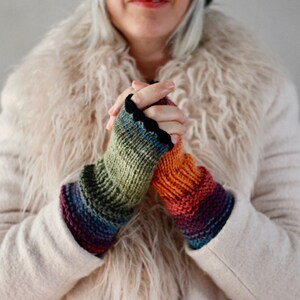 Puede incluir: Un par de guantes sin dedos de punto de colores con ribete negro. Los guantes los lleva una persona que lleva una chaqueta de piel sint&eacute;tica blanca.