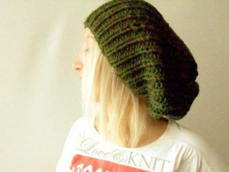 May include: A dark green knitted beanie hat. The hat is slouchy and has a ribbed texture.