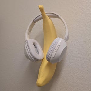 May include: White wireless headphones with a yellow banana hanging from the headband.