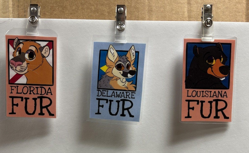 K&ouml;nnte beinhalten: Drei rechteckige Ausweish&uuml;llen aus Kunststoff mit Metallclips, die jeweils eine Cartoon-Tierillustration und Text zeigen. Die Ausweise tragen die Aufschriften FLORIDA FUR, DELAWARE FUR und LOUISIANA FUR mit einem Raubtier, einem Hund und einem B&auml;ren.
