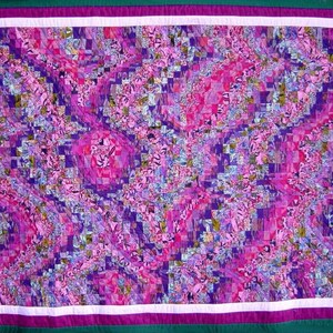 Peut inclure: Une courtepointe faite à la main avec un motif abstrait vibrant. La courtepointe présente un patchwork de petits carrés dans des tons de rose, de violet et de bleu, créant un motif tourbillonnant. Elle a une bordure blanche, une bordure violette et un dos vert.