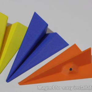May include: Three paper aeroplanes in yellow, blue and orange with a magnet on the orange aeroplane.  Magnet for easy installation.