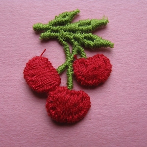 May include: Three red embroidered cherries with green stems and leaves.