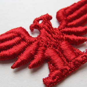 May include: Red embroidered eagle patch with detailed wings and a standing pose.