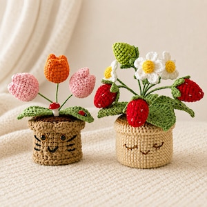 May include: Two crocheted potted plants. The left pot is tan with a cat face, holding pink and orange tulips and a small mushroom. The right pot is light beige with a sleepy face, holding white flowers, green leaves, and red strawberries.