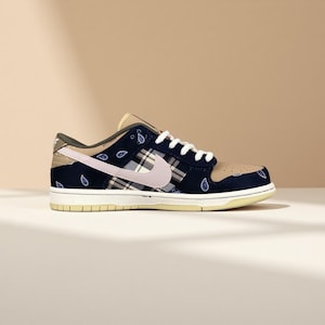 K&ouml;nnte beinhalten: Ein marineblauer und beigefarbener Sneaker mit Paisley- und Karomuster. Der Schuh hat einen hellrosa Swoosh, wei&szlig;e Schn&uuml;rsenkel und eine cremefarbene Sohle. Das Design umfasst eine beige Zehenbox und Fersenverkleidung.